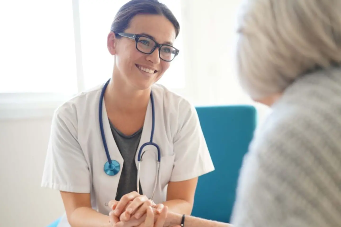 Un médecin souriant qui tient la main d'une patiente âgée, des services natifs d'AWS pour améliorer la sécurité