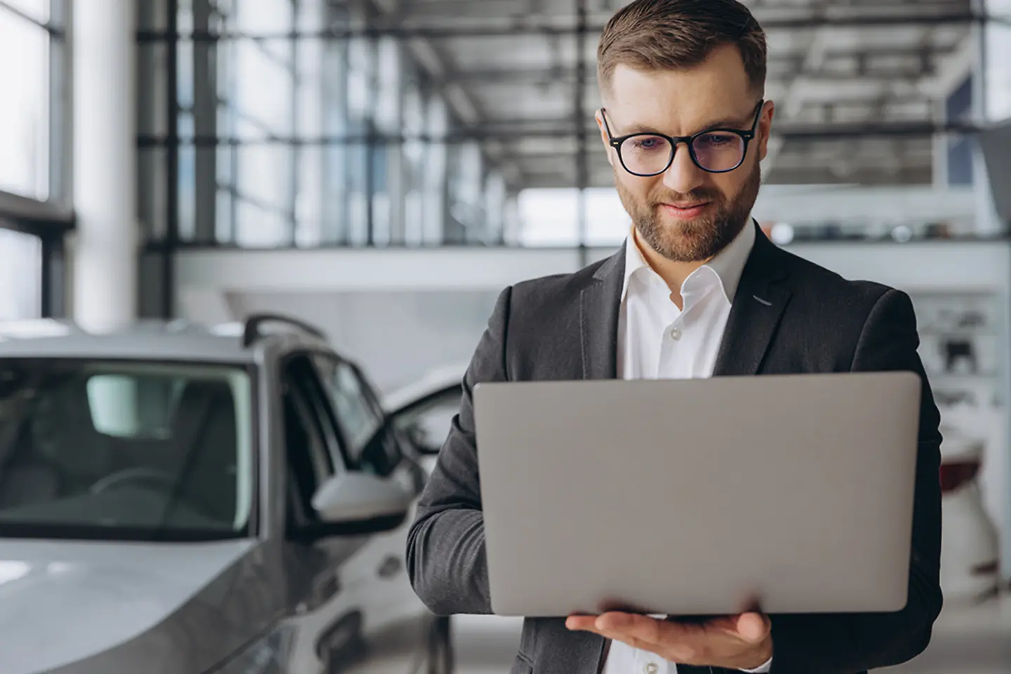 Vendedor de coches con un laptop en un concesionario
