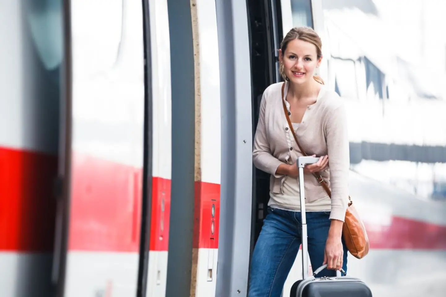 Frau mit Koffer vor einem Zug der Deutschen Bahn
