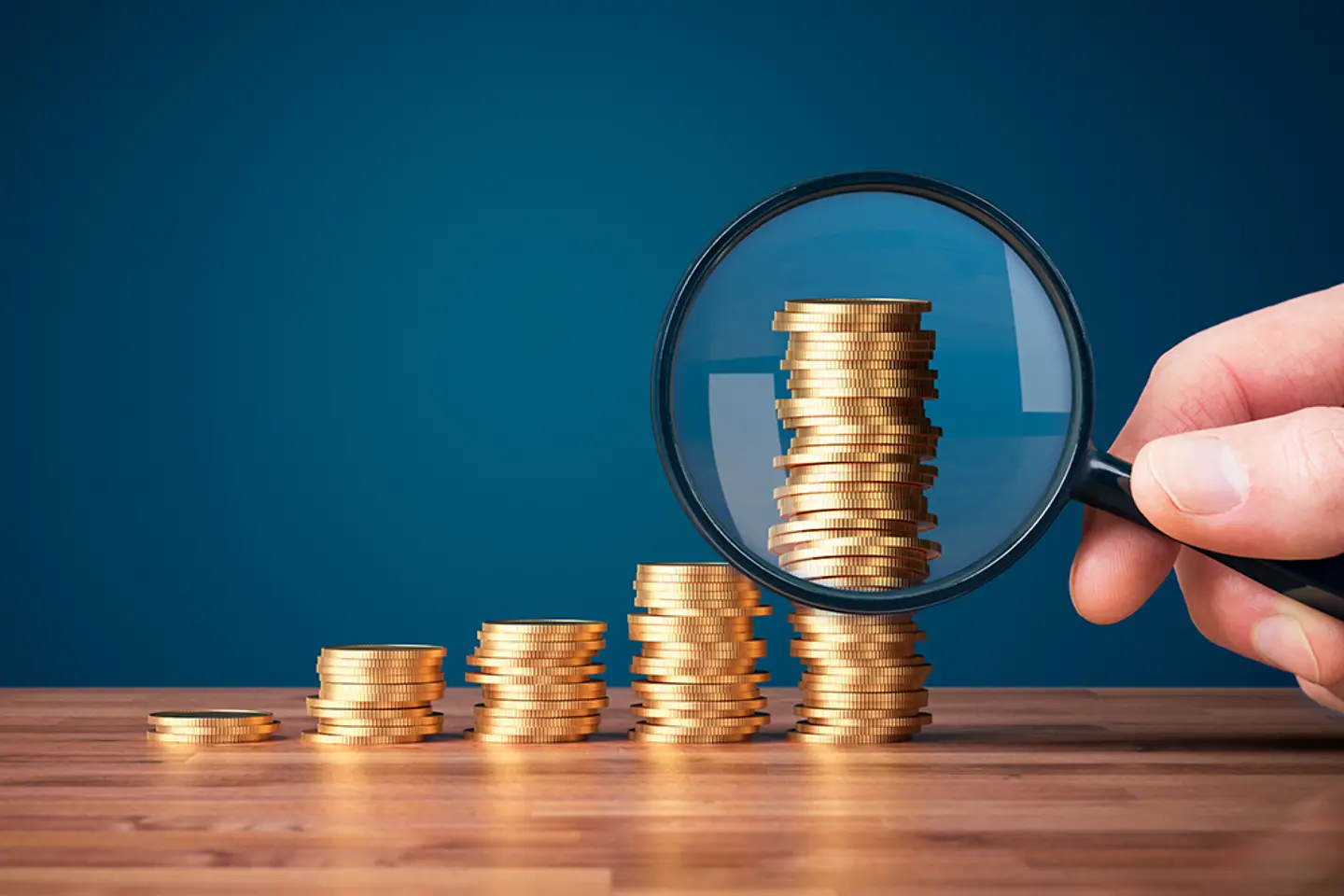 Coins stacked up with a magnifying glass in the foreground