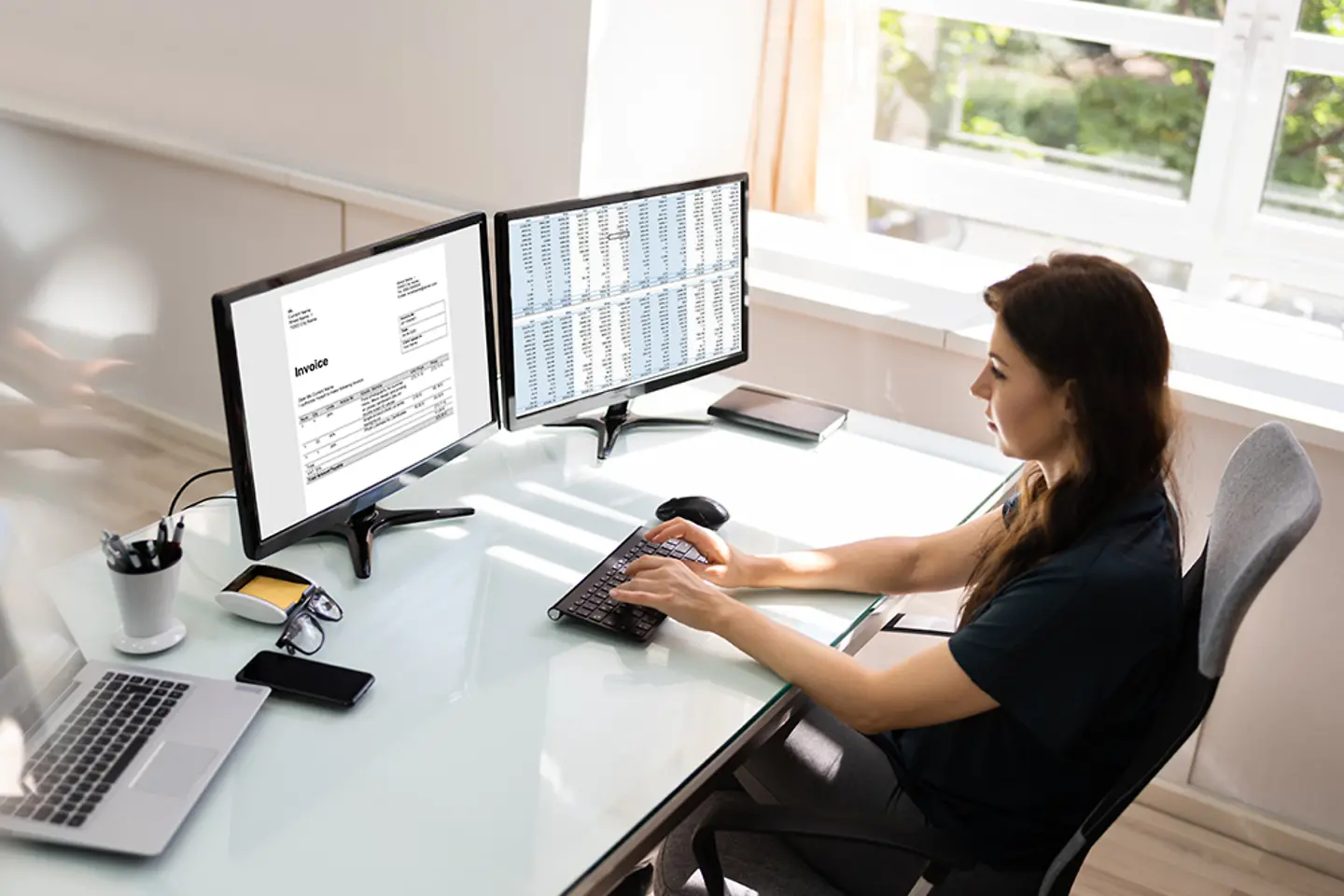 A female accountant uses e-invoice software on a desktop computer