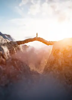 Man walking on an impressing mountain bridge into the sun