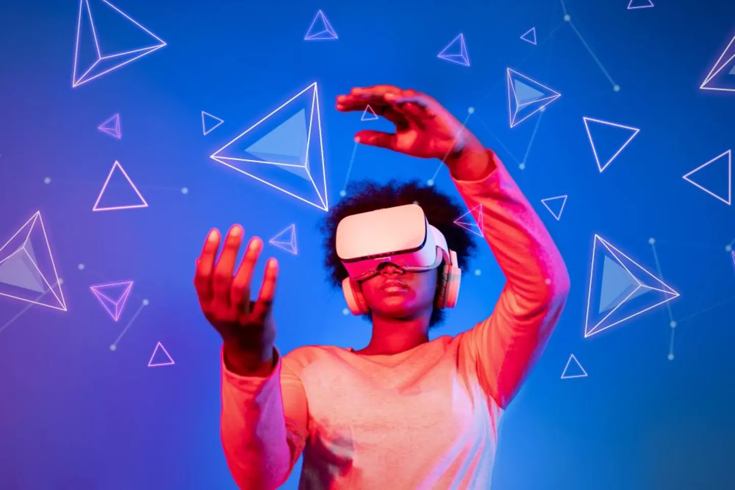 Frau mit VR-Brille vor einem blauen und pinkfarbenen Hintergrund betrachtet schwebende geometrische Formen