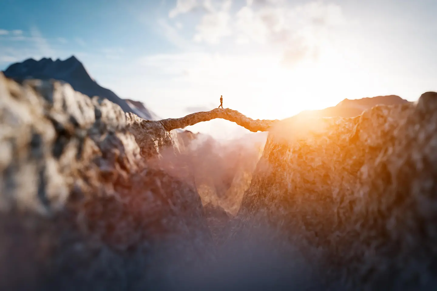 Um homem caminha em direção ao sol em uma impressionante ponte na montanha