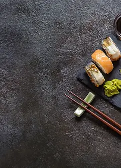 Sushi Rollen mit Reis, Fisch, Sojasauce auf einem dunklen steinernern Hintergrund