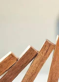 A hand halts wooden dominoes from falling over, symbolizing the prevention of a business crisis