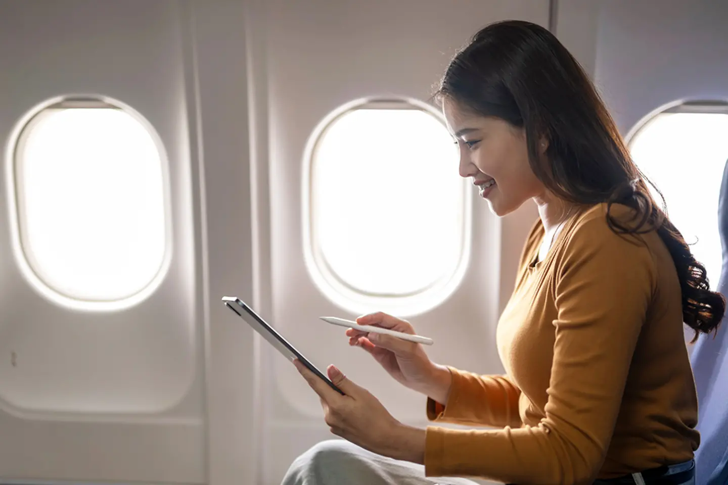 Young businesswoman working on tablet during flight
