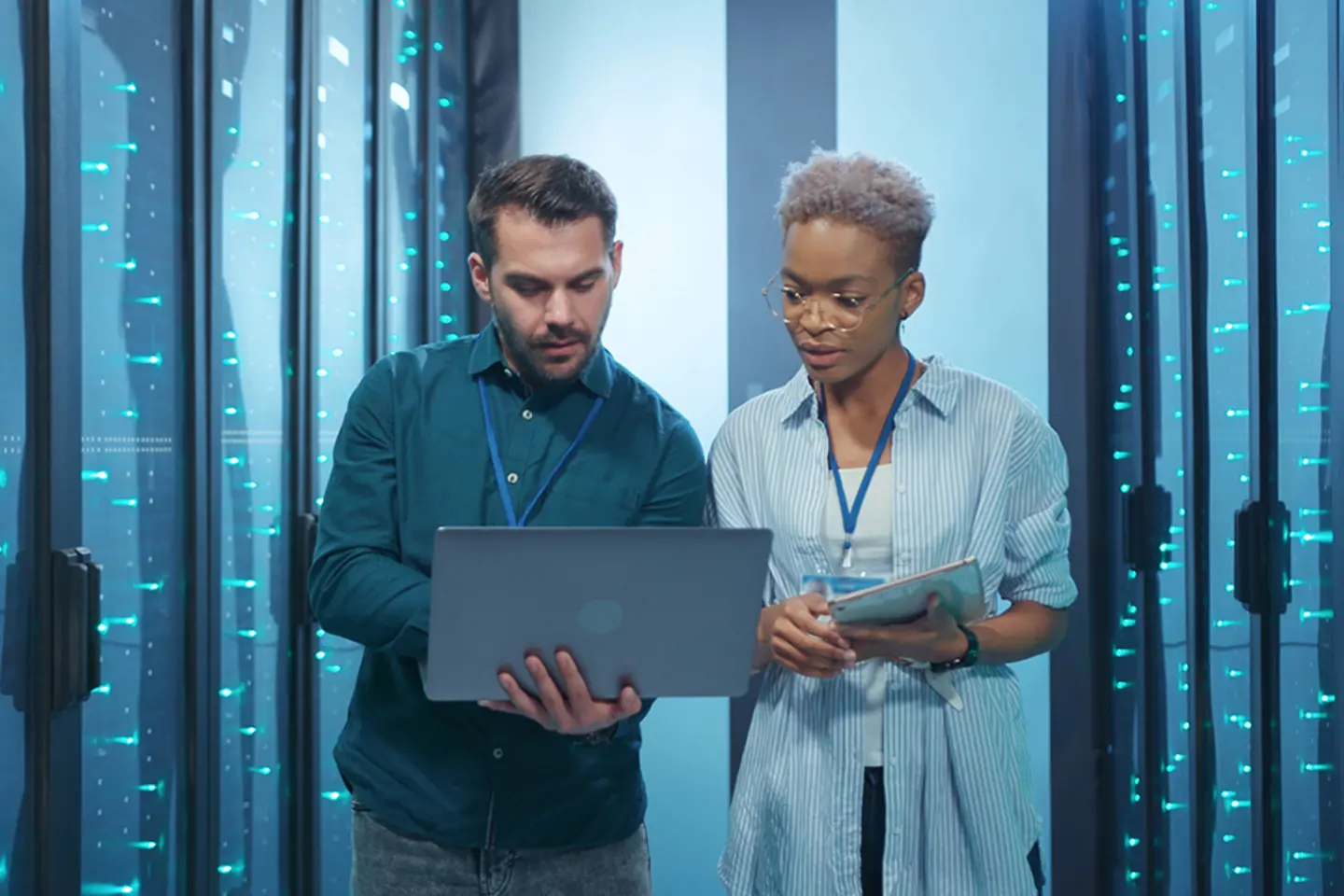 Two cloud specialists checking data on tablet in data center