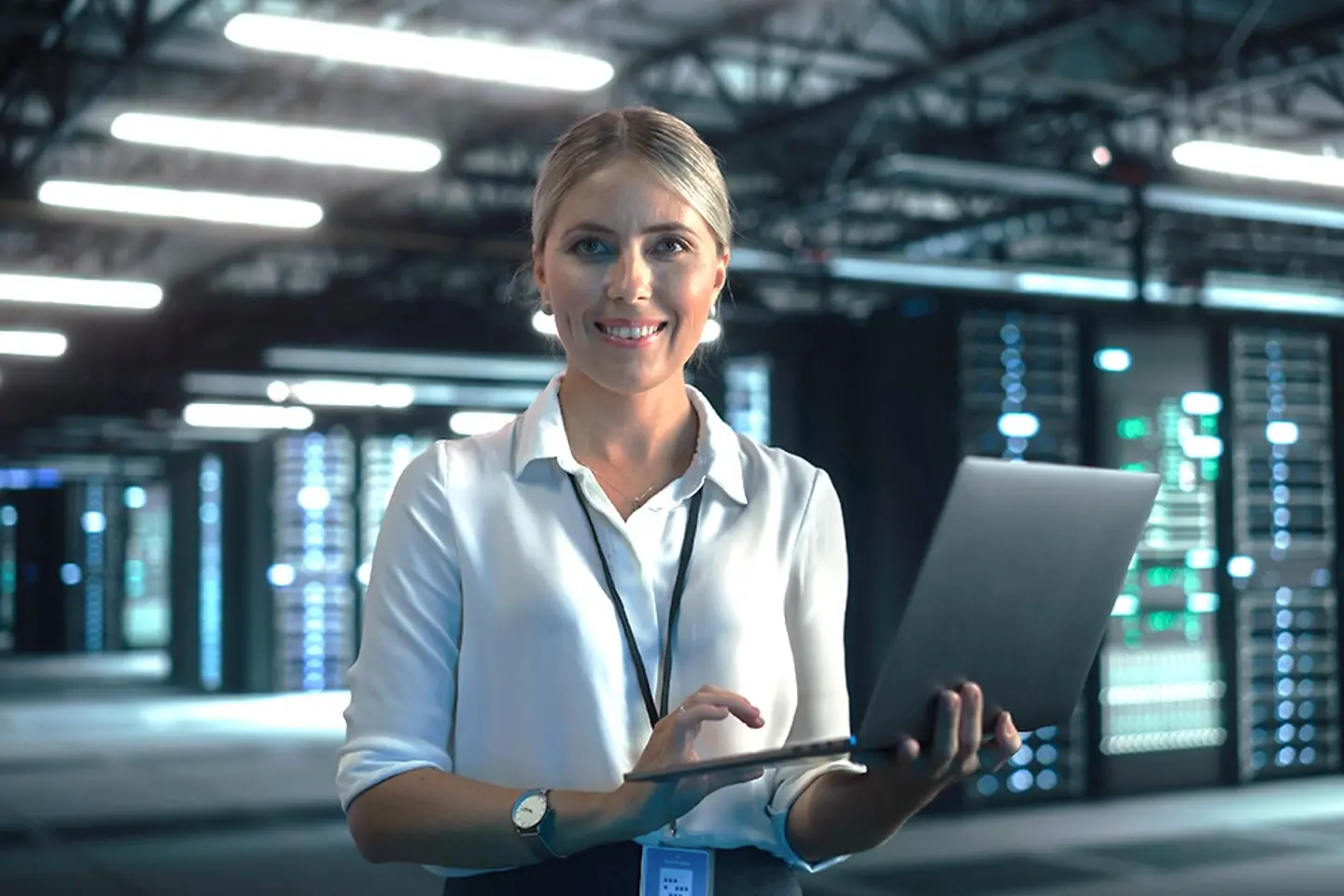 Female cloud expert checking data on laptop in data center