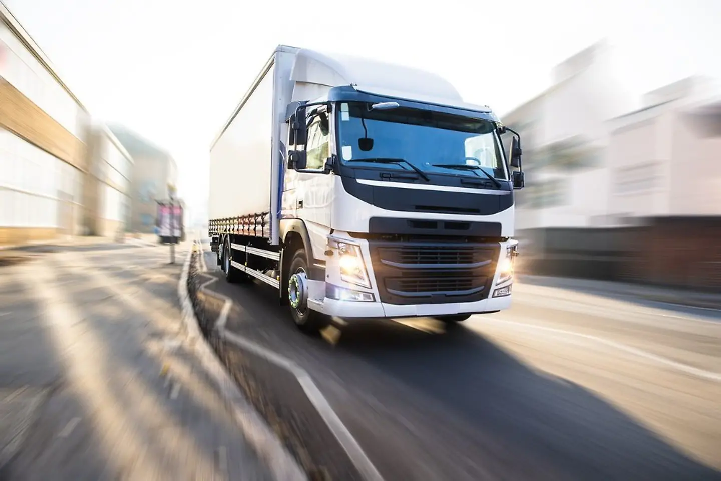 Een witte vrachtwagen die een stad doorkruist.